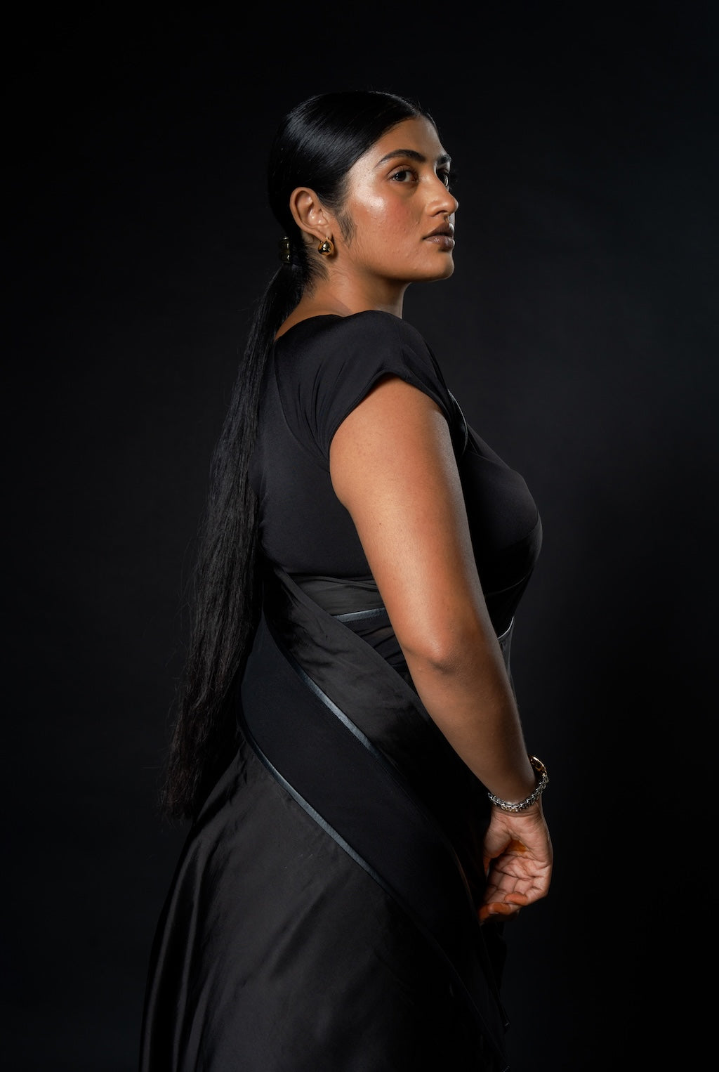 Woman posing in a black Rebel Roots Saree against a dark background