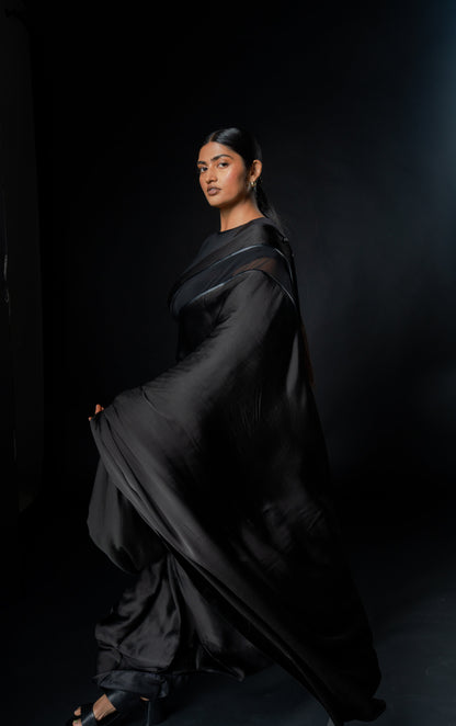 Woman in a black saree against a dark background