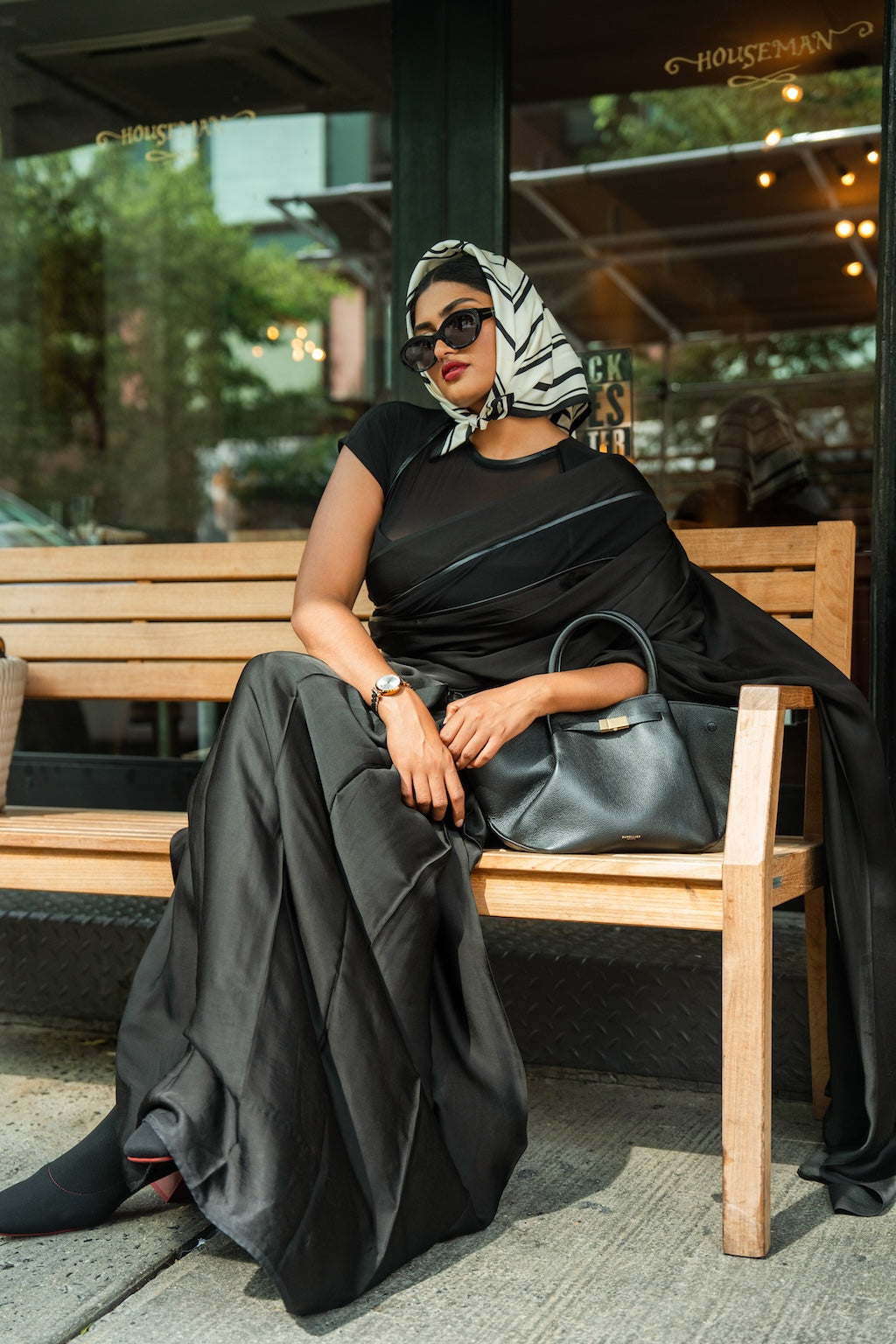 Woman in a black Rebel Roots Saree with a Scarf chilling on a bench outdoors. 