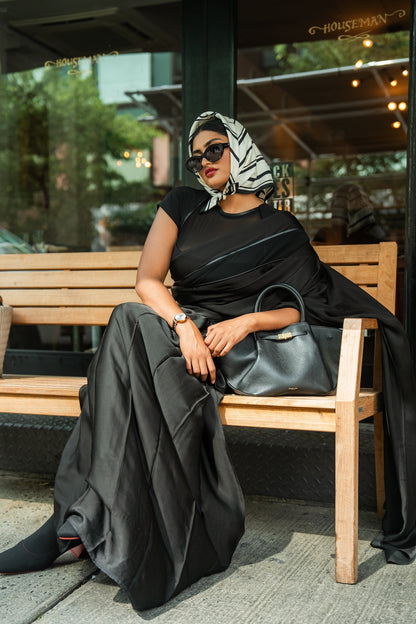 Woman in a black Rebel Roots Saree with a Scarf chilling on a bench outdoors. 