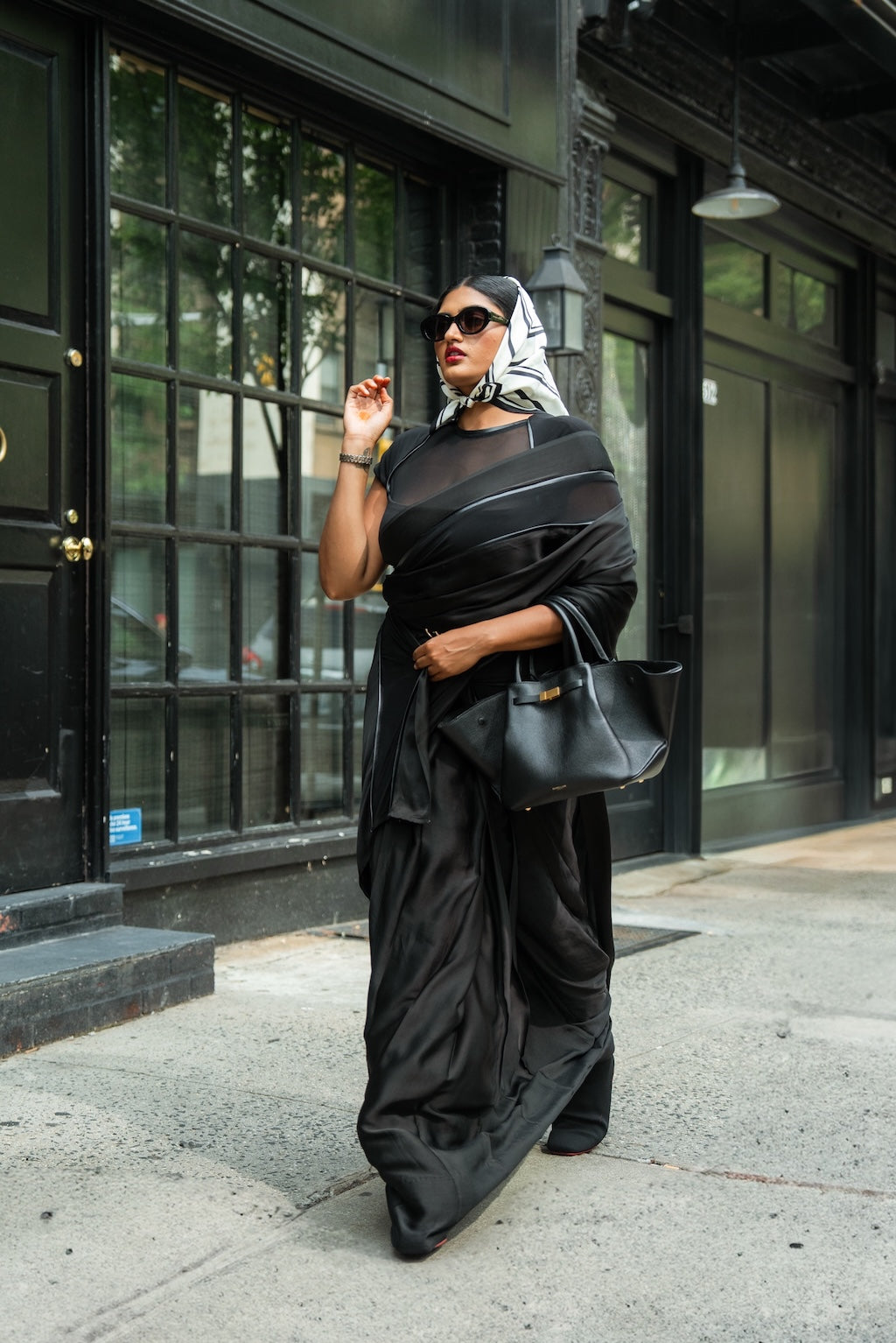 Woman in a black Label Rebel Roots Capsule Ready to Wear Saree standing on a city street.