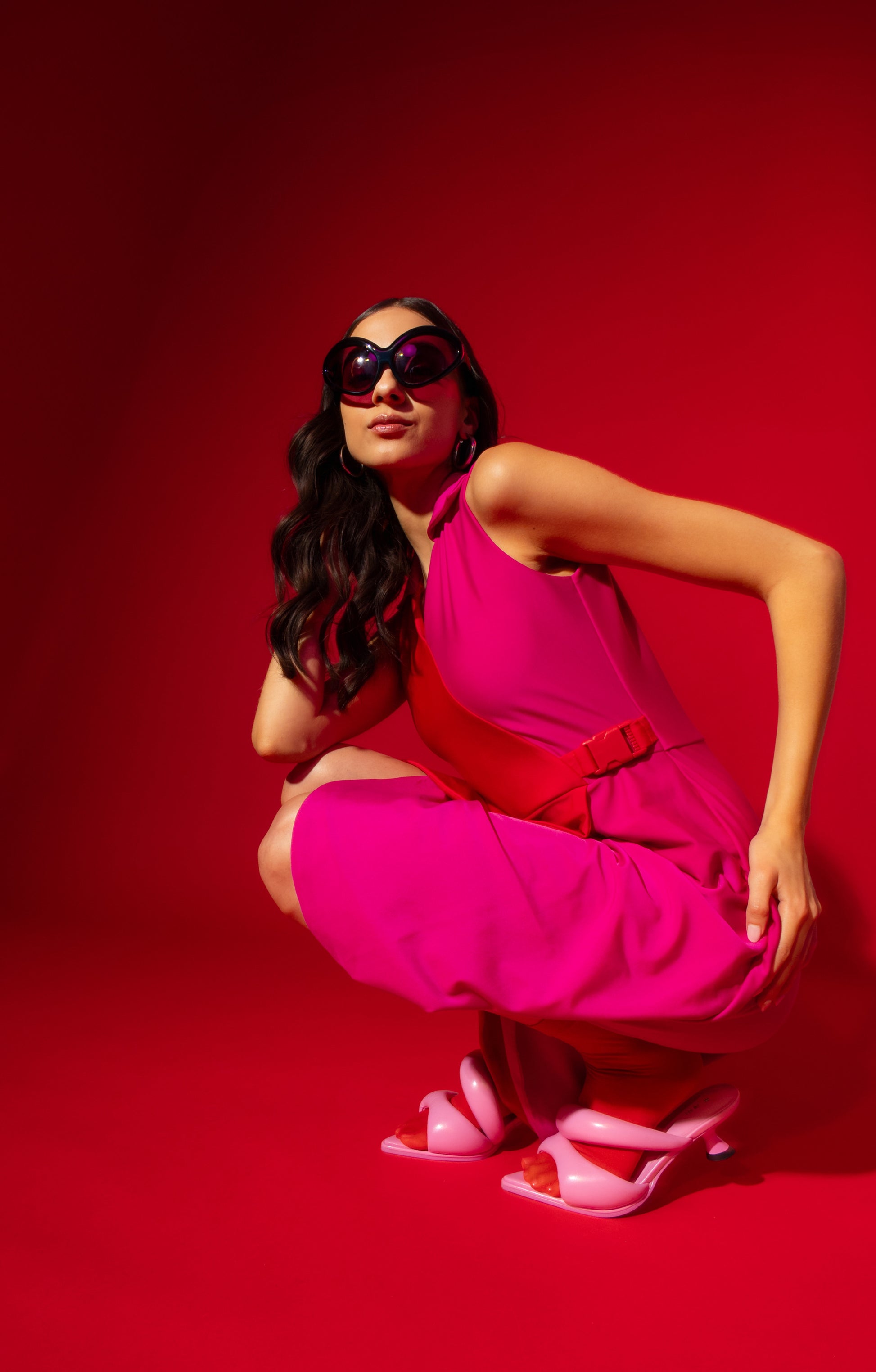 Woman in a bright pink outfit posing on a red background