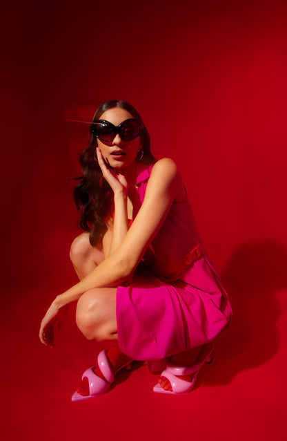 Woman in a pink outfit posing against a red background