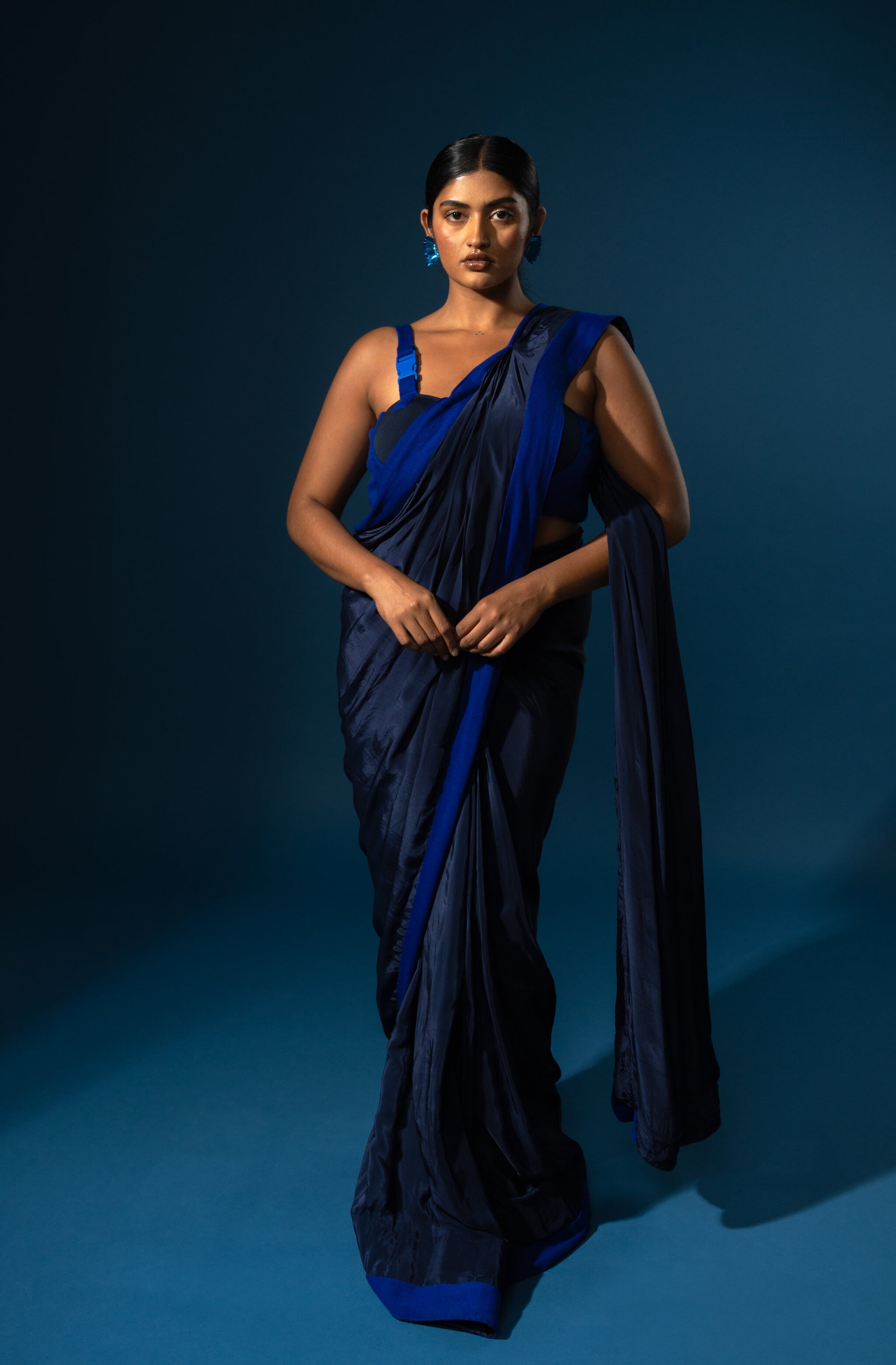 Woman wearing a blue saree against a dark blue background
