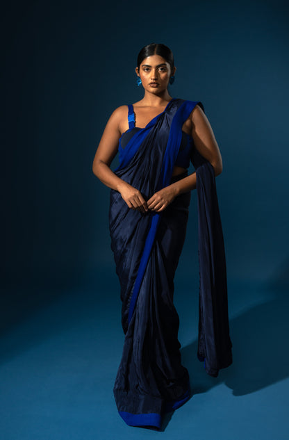 Woman wearing a blue saree against a dark blue background