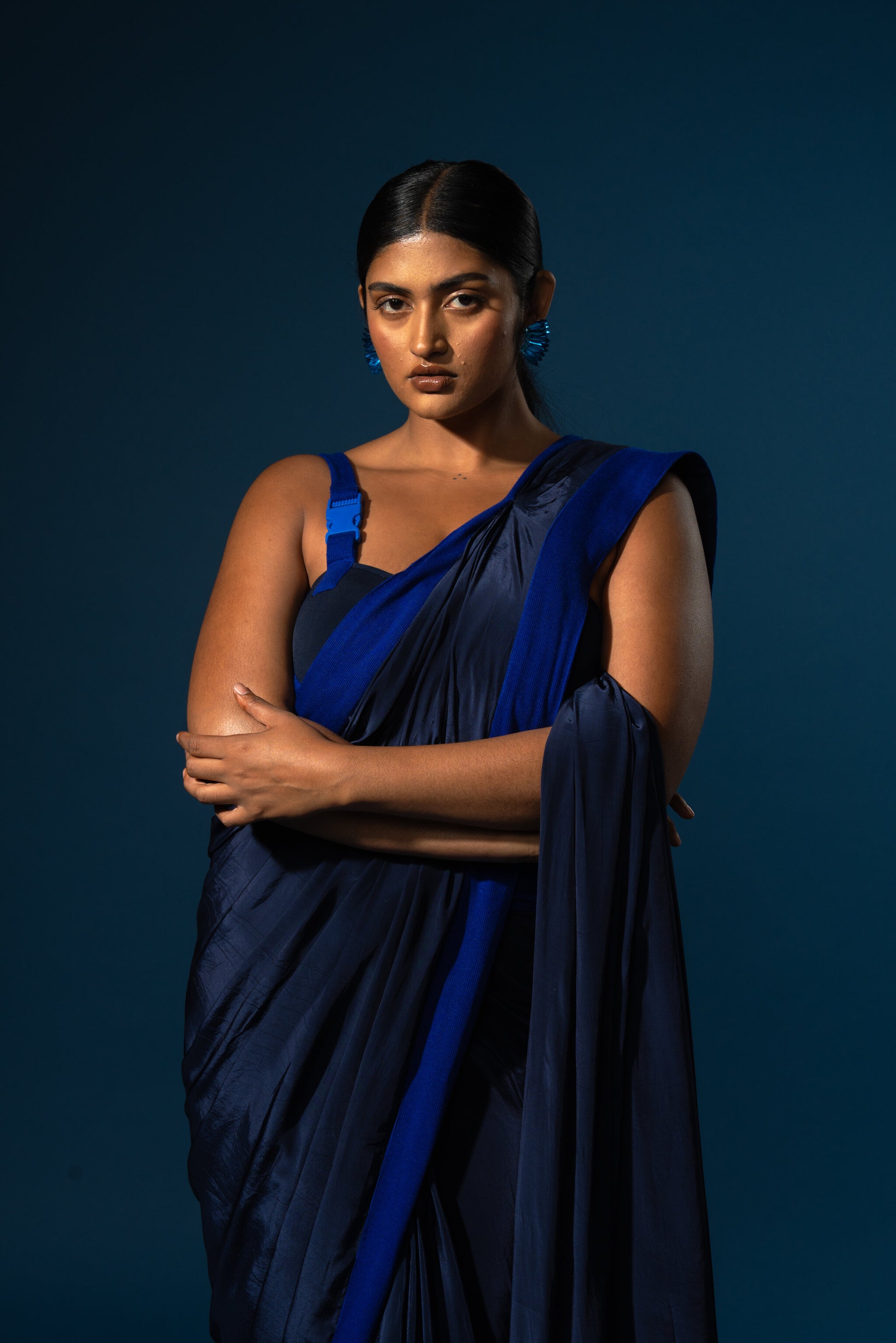 Woman wearing a blue saree against a dark background