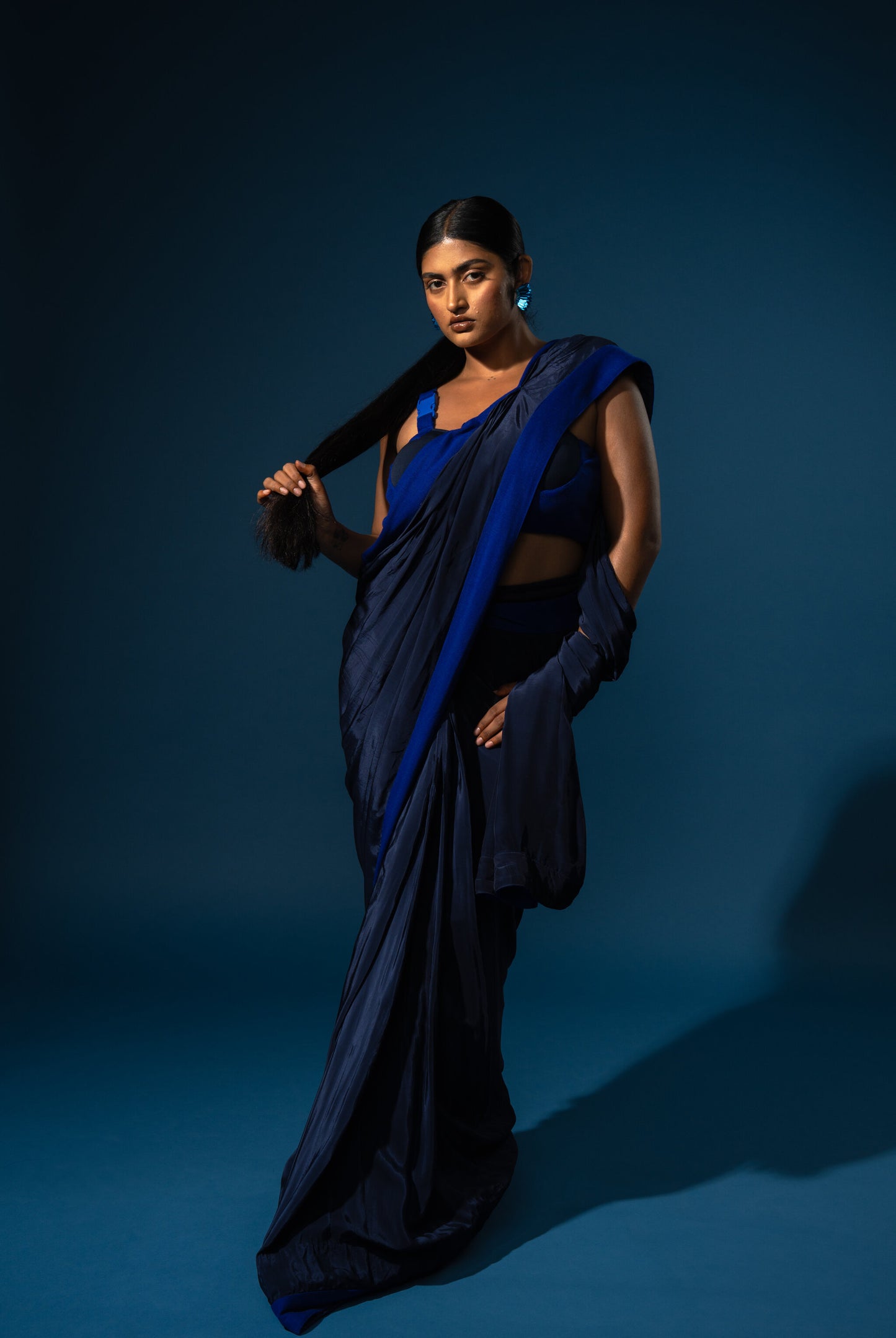 Woman in a blue saree against a dark blue background