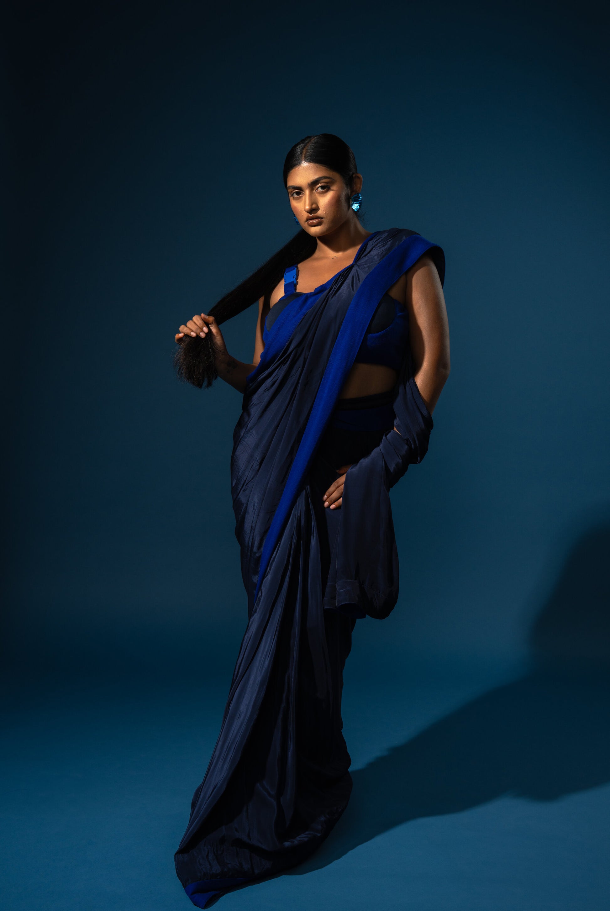 Woman in a blue saree against a dark blue background