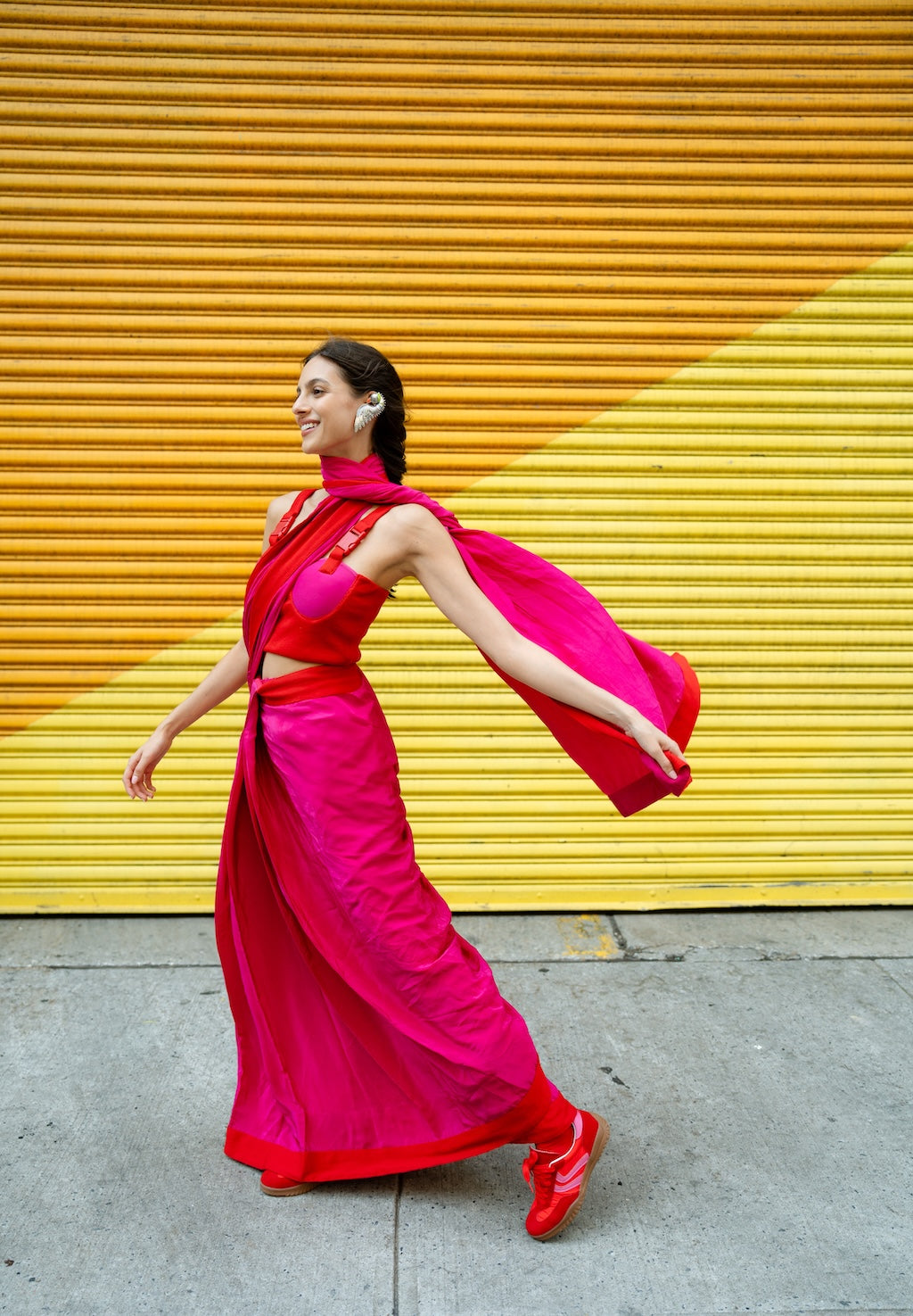 Woman in a bright pink Rebel Roots Buckle Saree against a yellow wall