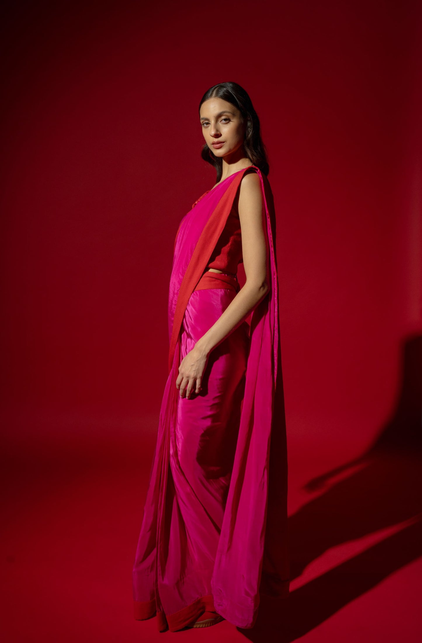 Woman in a bright pink saree with a red background