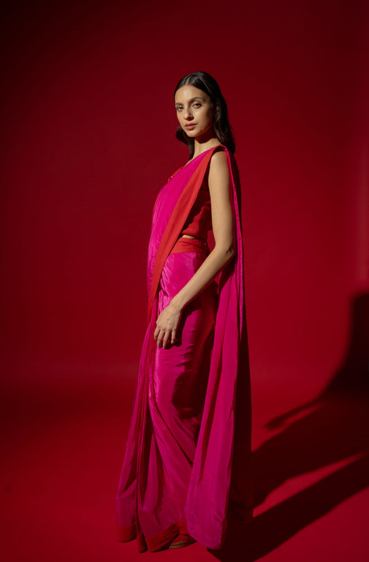 Woman in a bright pink saree with a red background