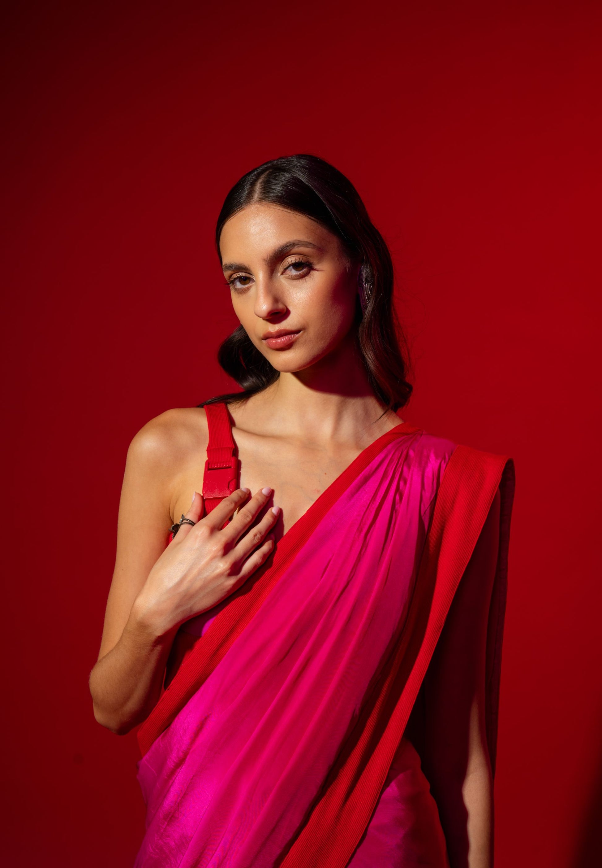 Woman wearing a bright pink saree against a red background