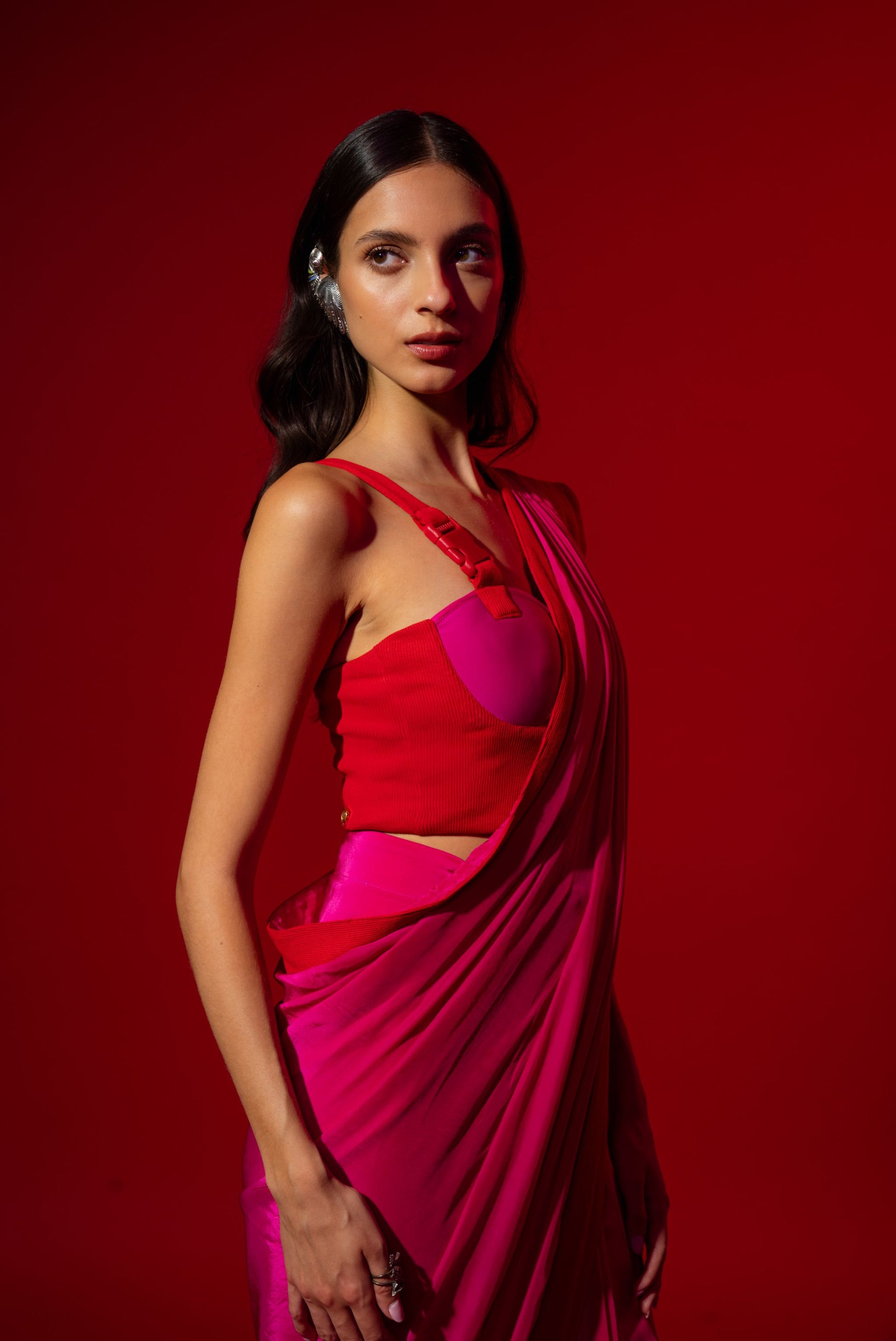 Woman wearing a red and pink saree against a red background