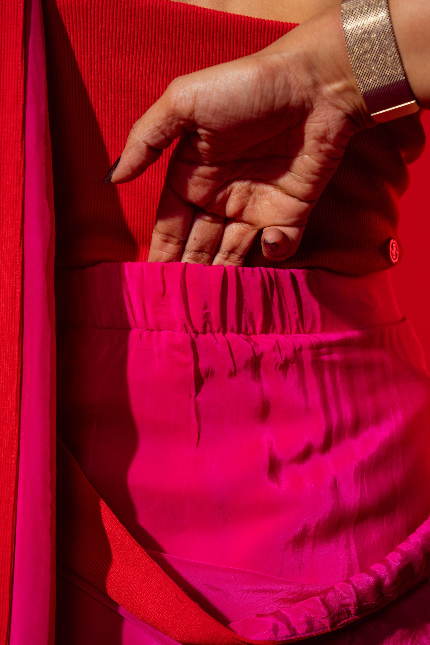 Close-up of a hand holding a pink fabric against a red background