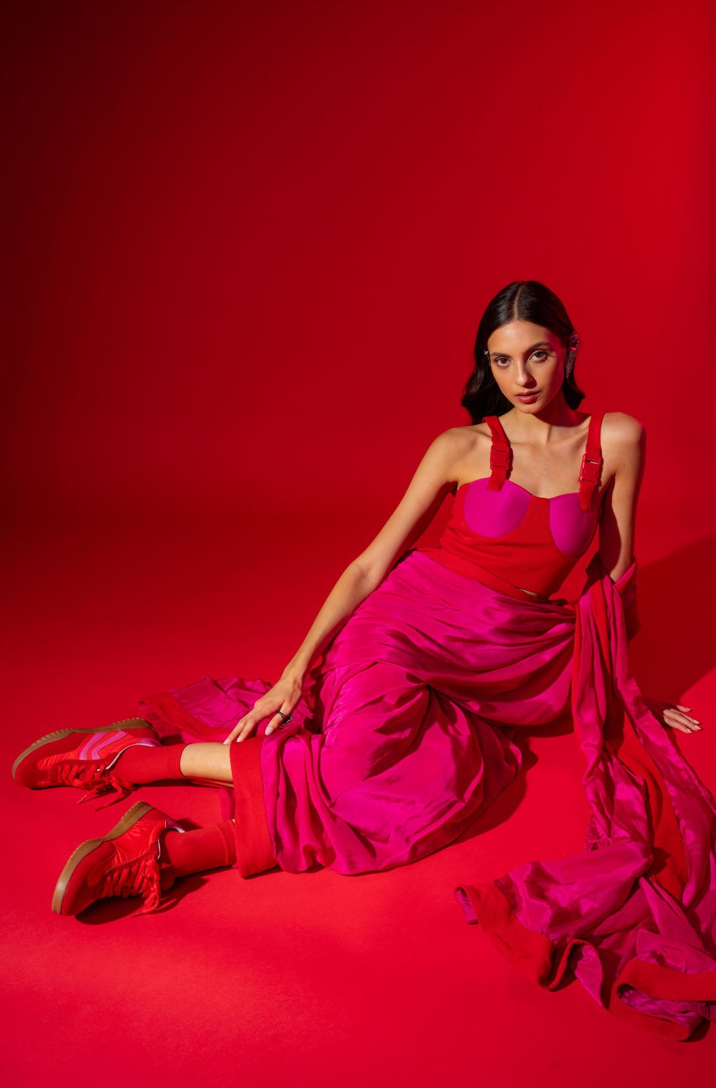 Woman in a vibrant red dress sitting on a red background