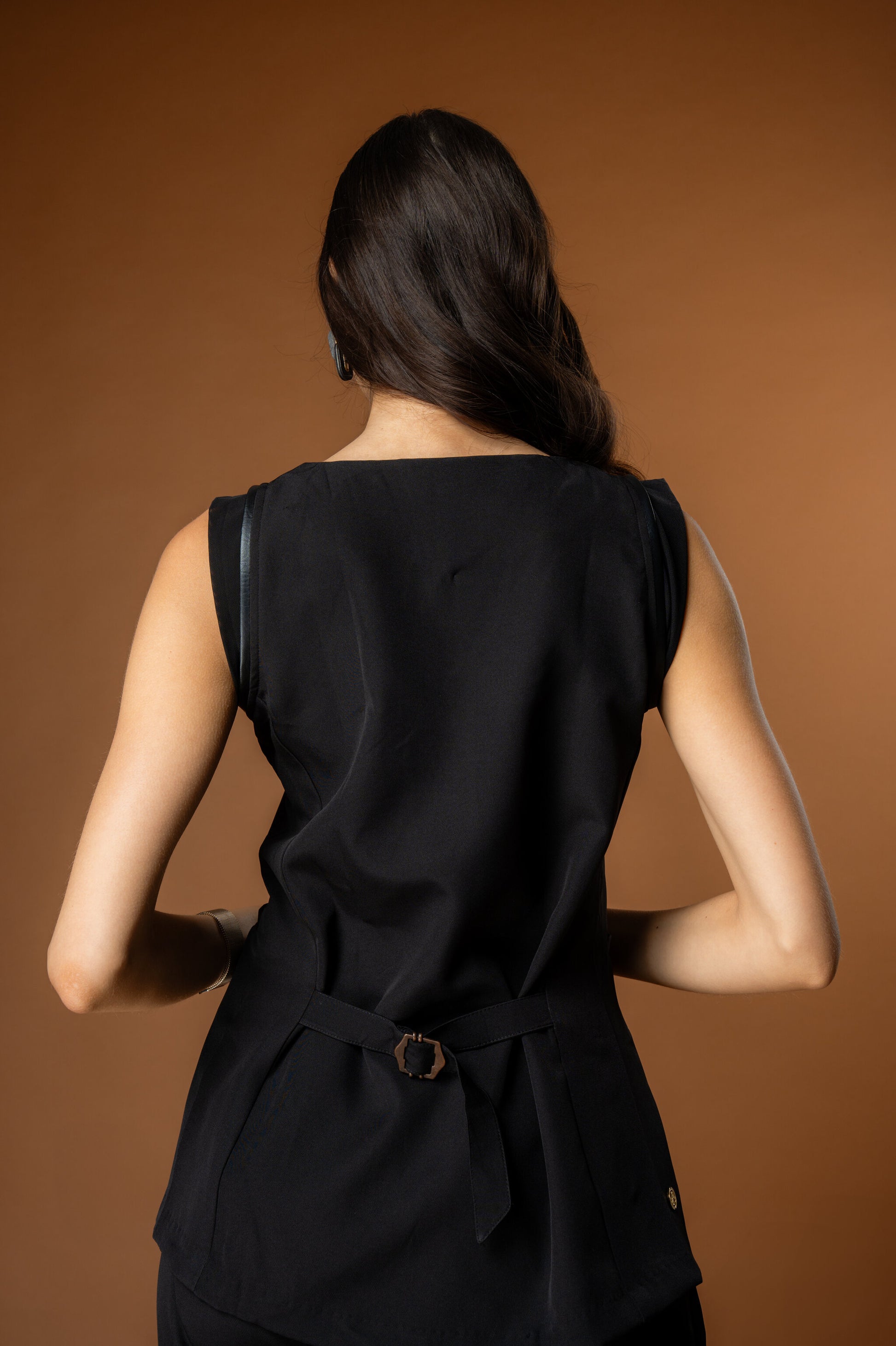 Woman wearing a black sleeveless waistcoat with a buckle in the back