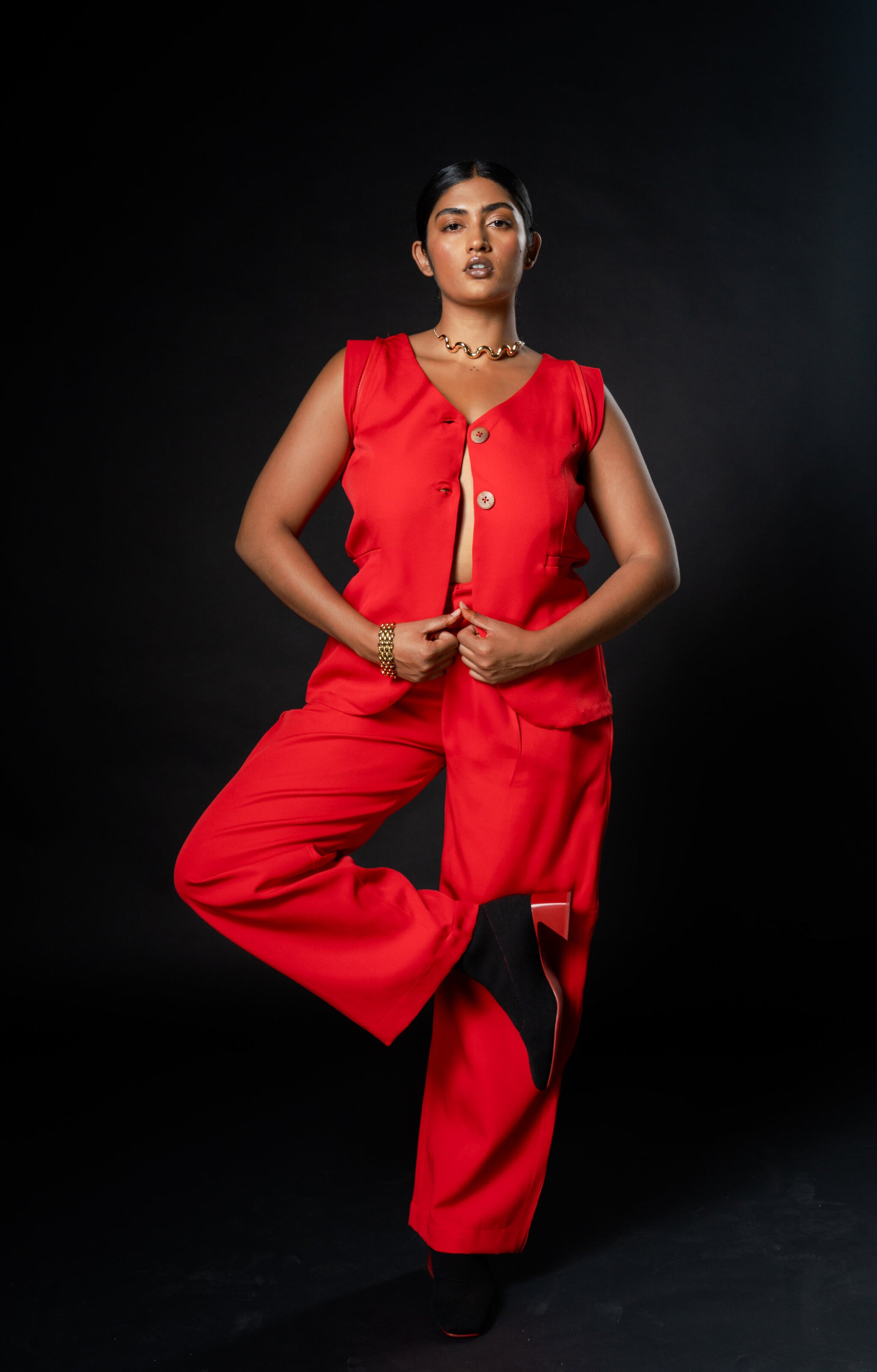 Woman in a red Waistcoat and red trousers, Rebel Roots Capsule Powerset, posing against a black background.