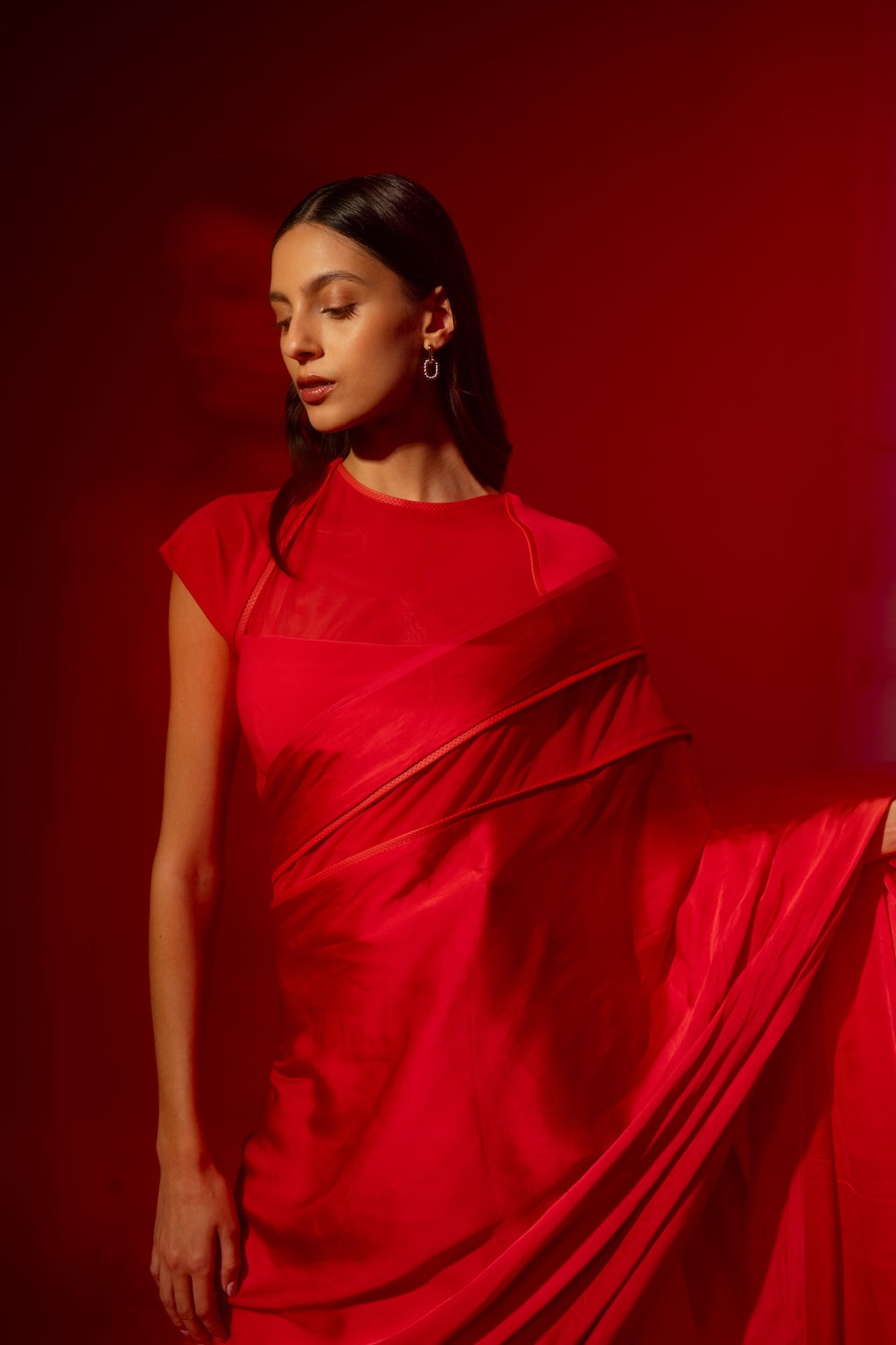 Woman wearing a red Rebel Roots Ready to Wear Saree standing against a red background