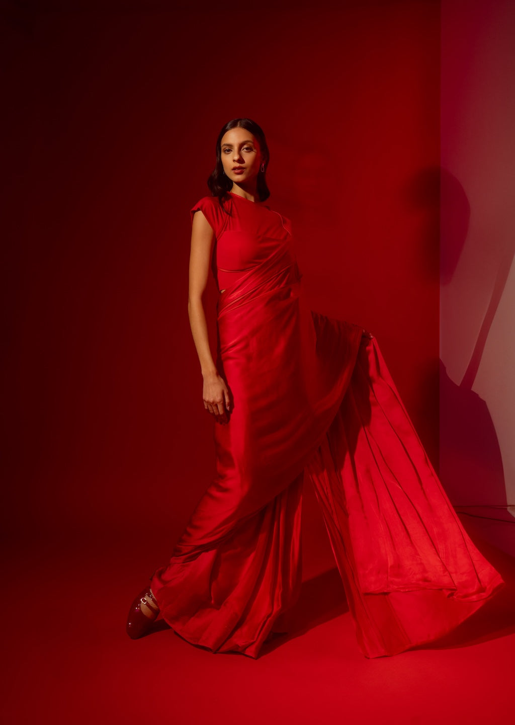 Woman in Label Rebel Roots red Ready to Wear saree standing against a red background