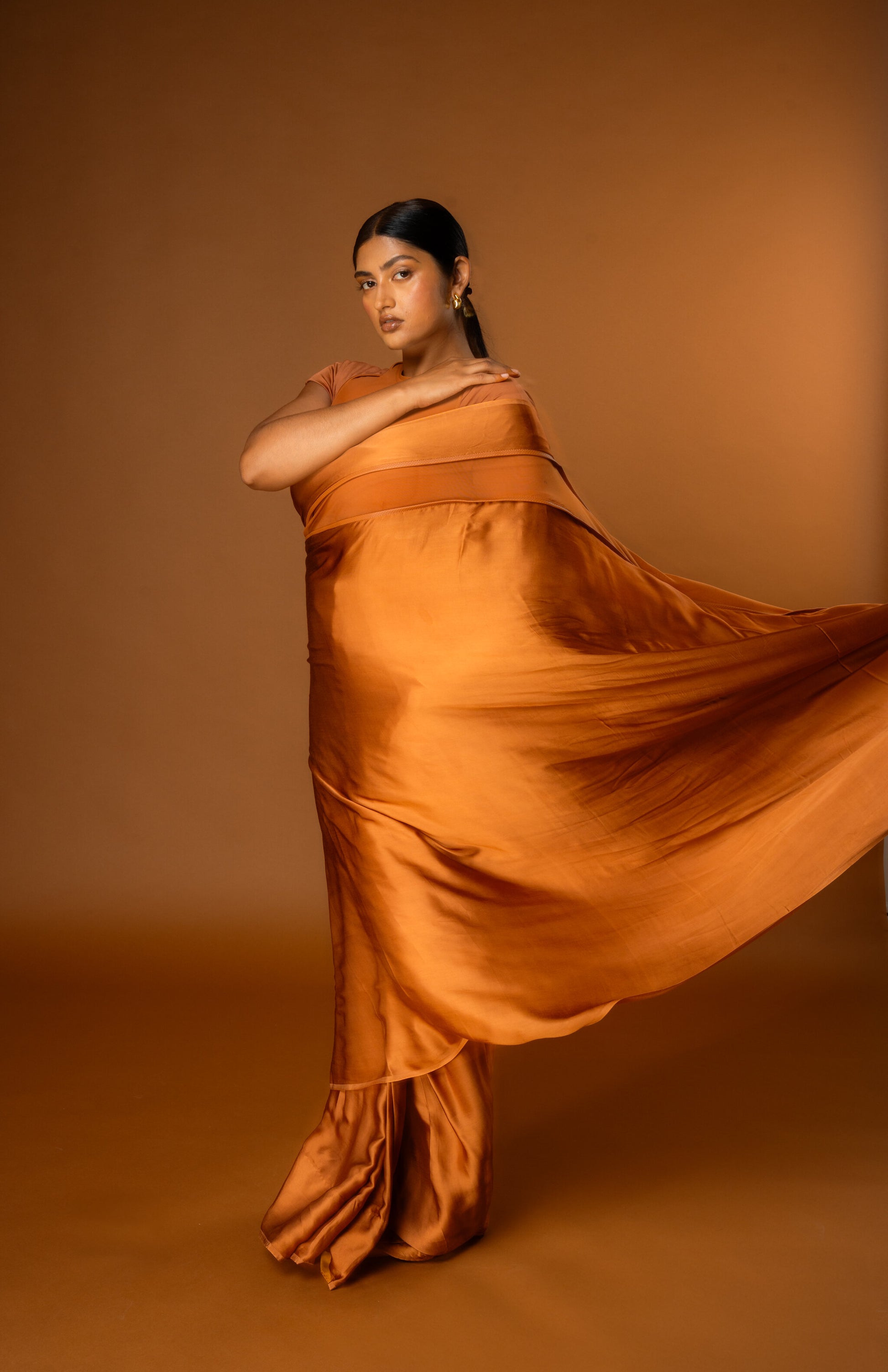Woman wearing a flowing orange Satin Pre-stitched Saree - Rebel Roots Capsule Tan Saree pre-stitched with blouse.