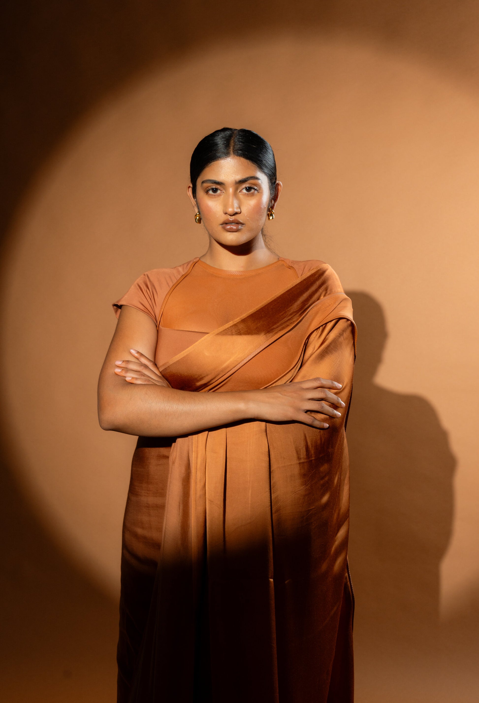 Modern Woman wearing a Tan saree. Saree has modern blouse with net stitching. The Rebel Roots saree is pre stitched