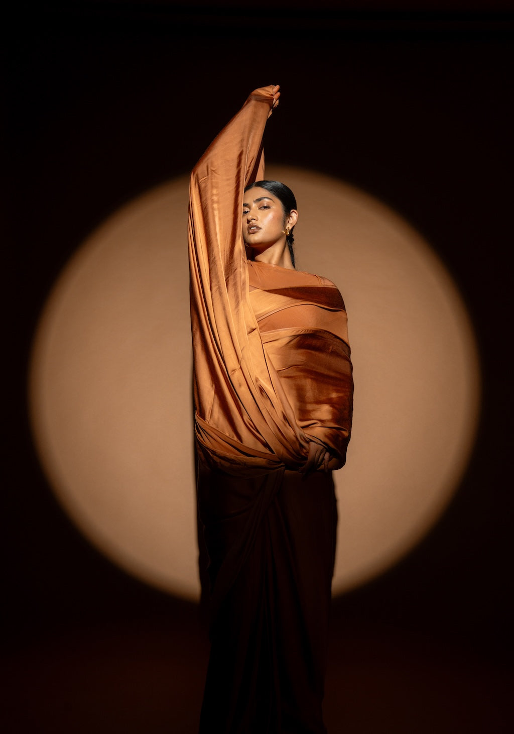 Person wearing Rebel Roots Tan Capsule Ready to Wear Saree. Woman stands under a spotlight comfortable in her saree.